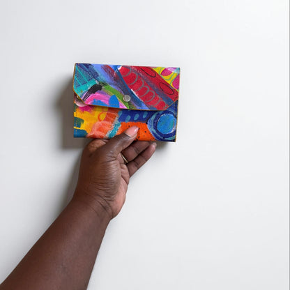 Colorful clutch held by a hand against a white background